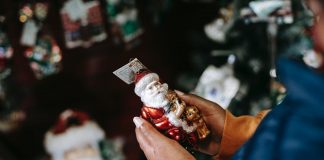 crop black person with decorative santa claus in shop