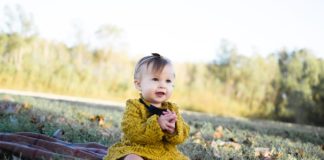 baby wearing yellow crochet long sleeve dress sitting on brown textile